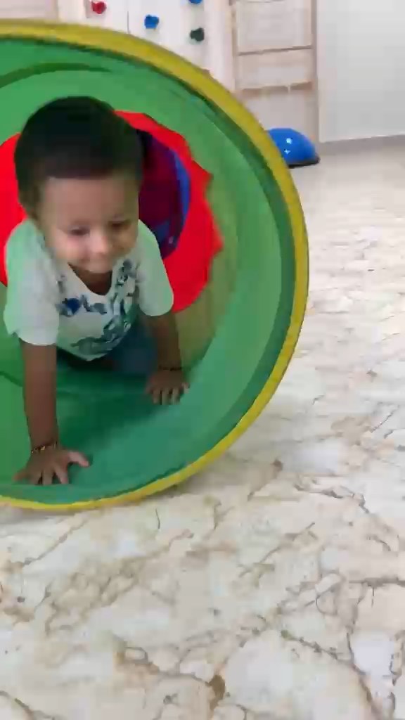 Toddler crawling through a play tunnel at Vasishtha School