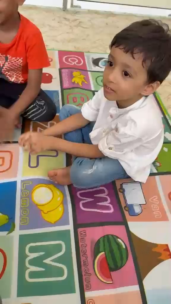 Children playing with alphabet mat and blocks at Vasishtha School