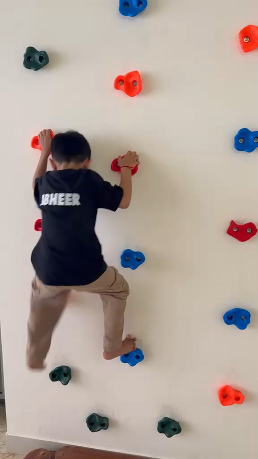 Child climbing the activity wall at Vasishtha School